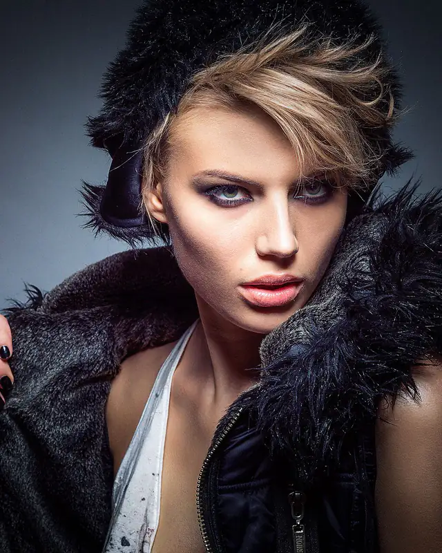 Portrait d’une femme en veste à col de fourrure noire, regard face à l’objectif.